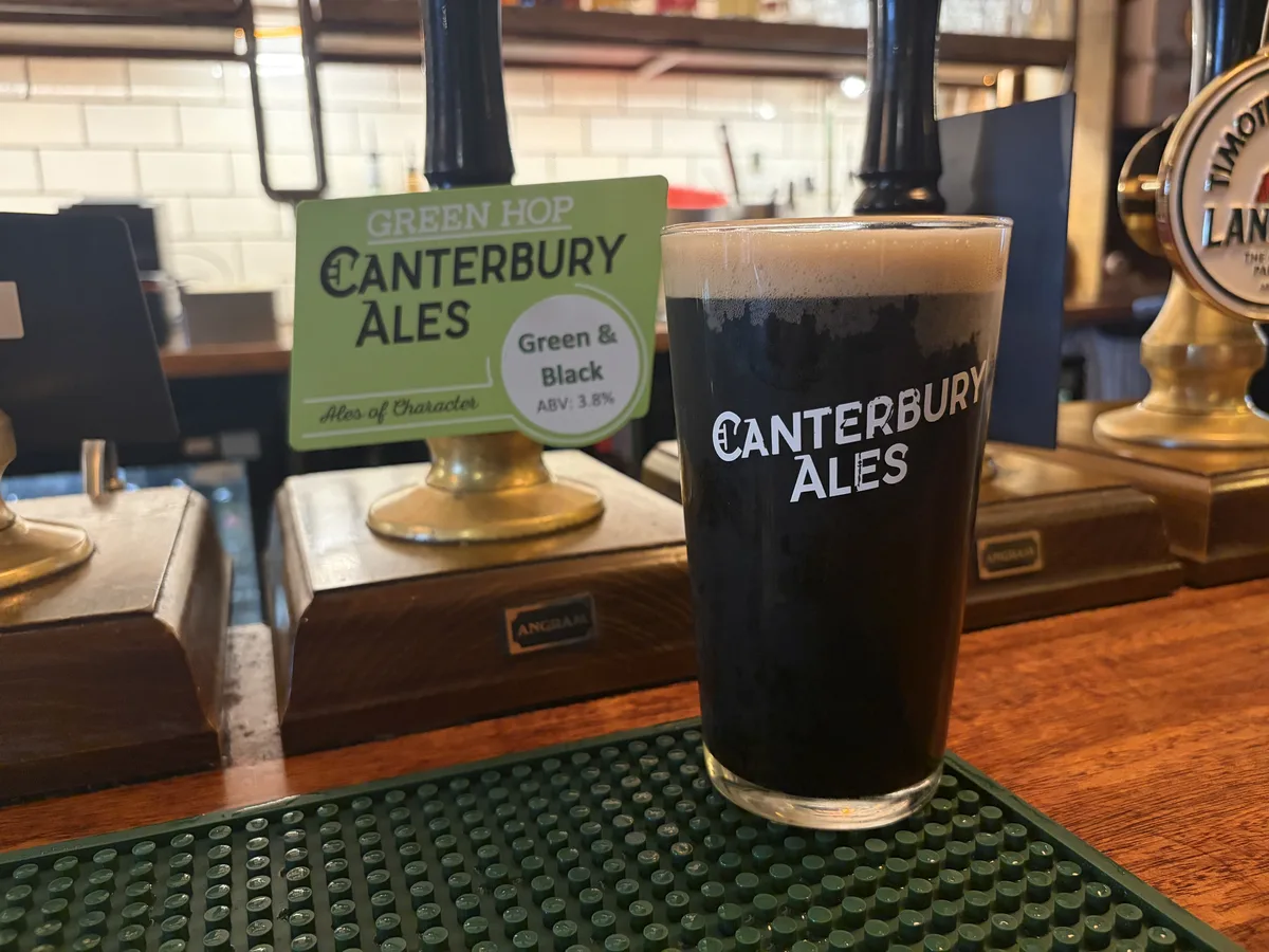 A dark pint of Green & Black on the bar at The Pullman, beside its Canterbury Ales pump clip