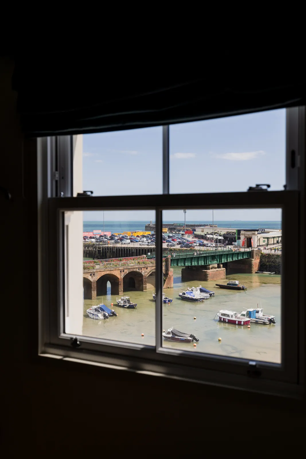A sash window in Room 9 looking out over Folkestone Harbour, the viaduct arches and moored boats
