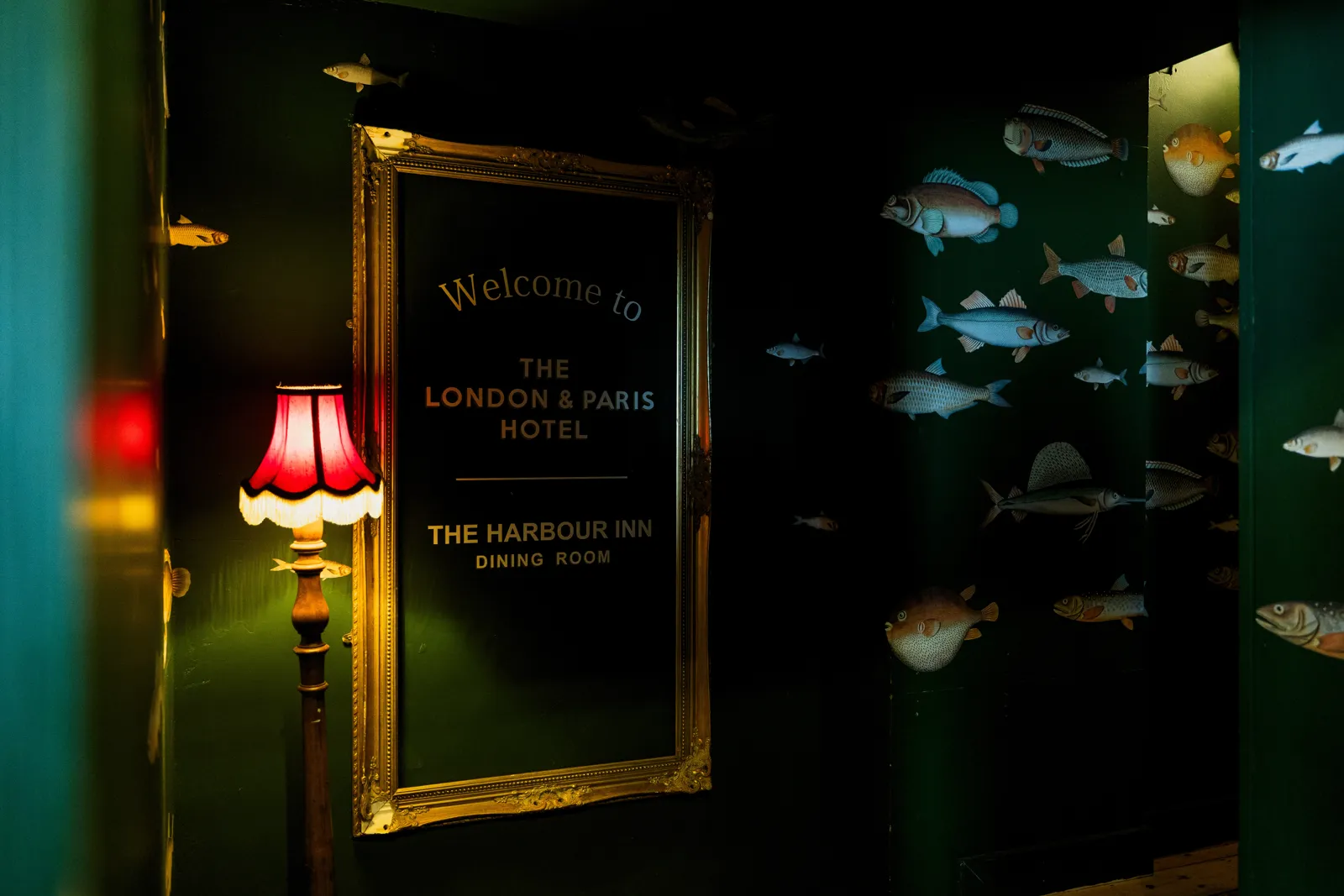 A gilt 'Welcome to London & Paris Hotel' sign beside a red lamp
