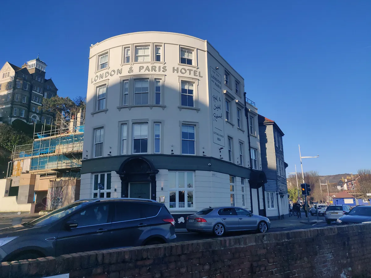 London & Paris Hotel’s curved cream front on Harbour Street, with its name across the top, under a blue sky