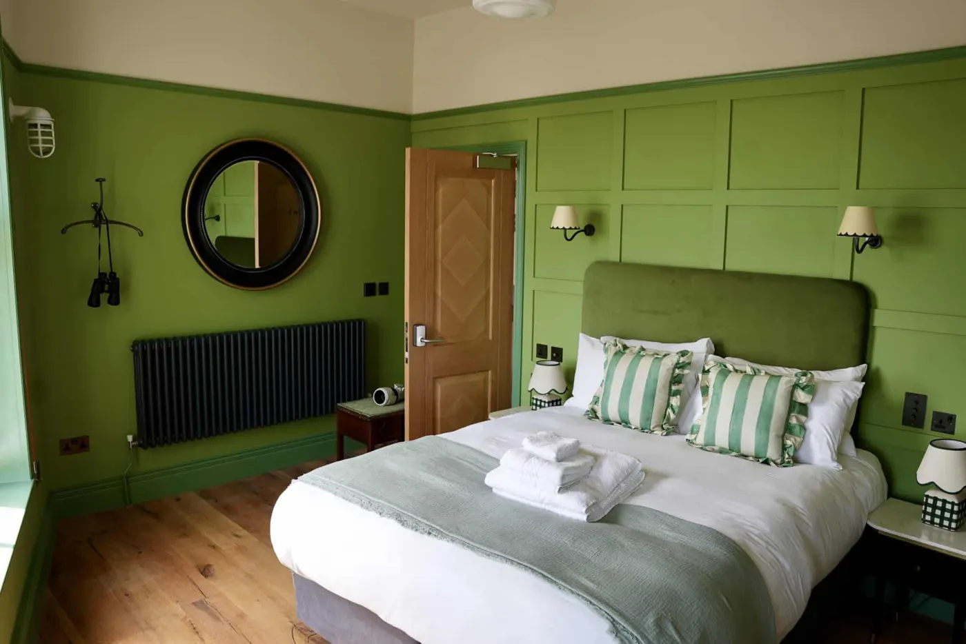 Room 2: a bed with a sage-green headboard against panelled green walls