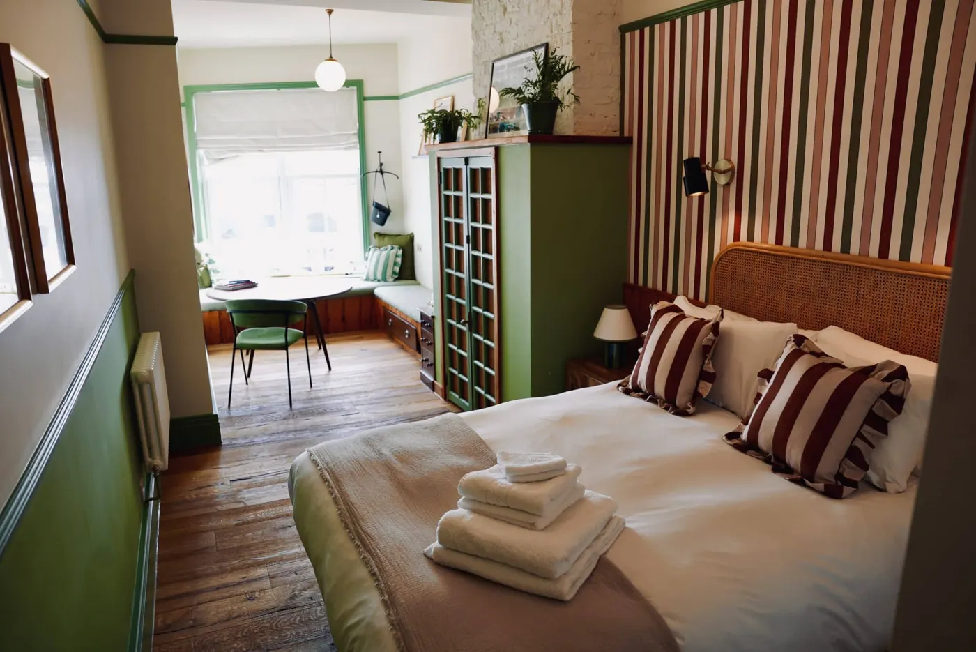 Room 3: a striped headboard and a table by the window