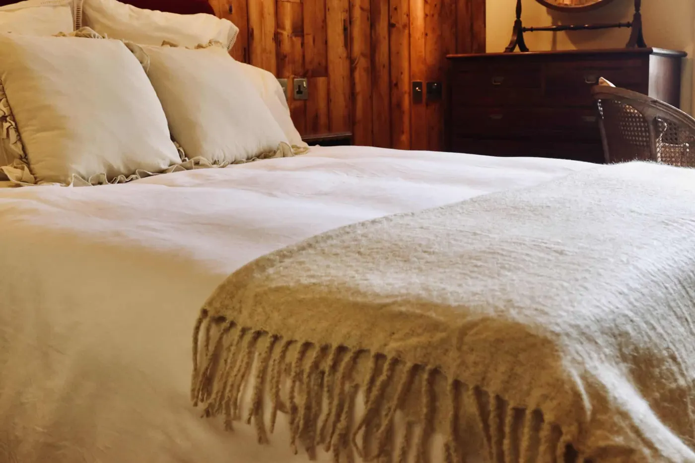 A double room with a cream throw against a timber-panelled wall
