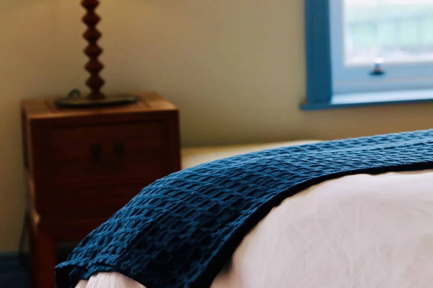 Room 6: a bed with a blue knitted throw beside a wooden chest of drawers