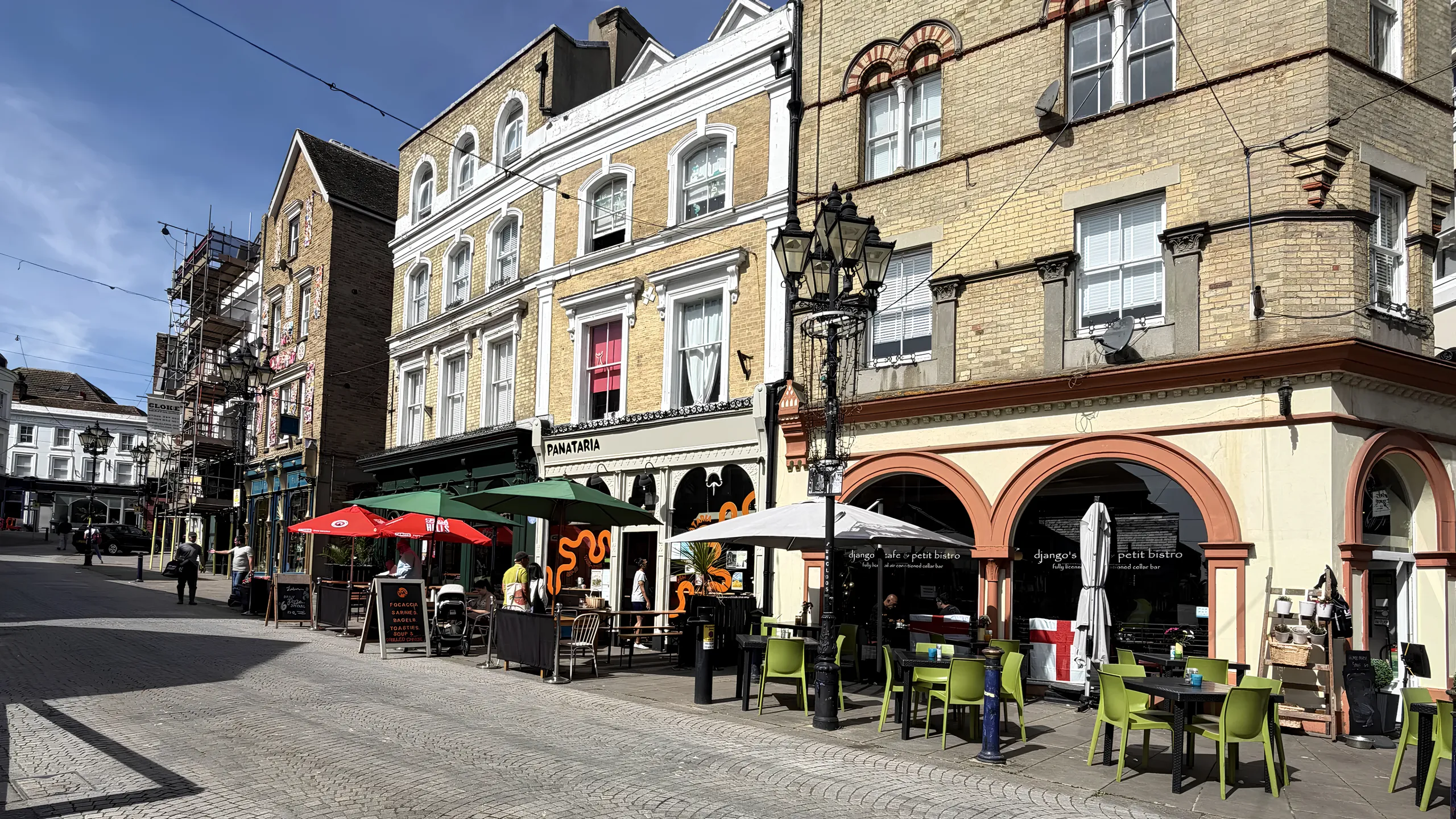 Folkestone’s cobbled Old High Street on a sunny day, with café tables, parasols and old shopfronts