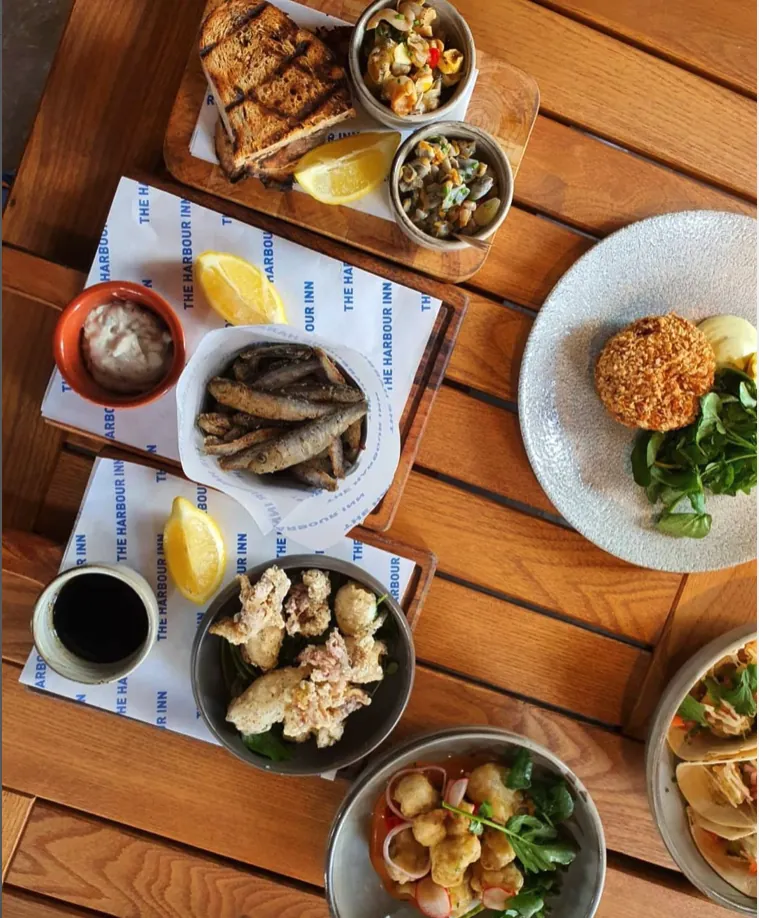 Small seafood plates to share, laid out on a wooden table with lemon and dips