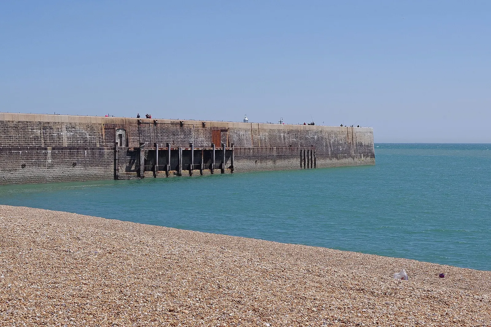 Folkestone Harbour Arm seen across the shingle beach on a clear day