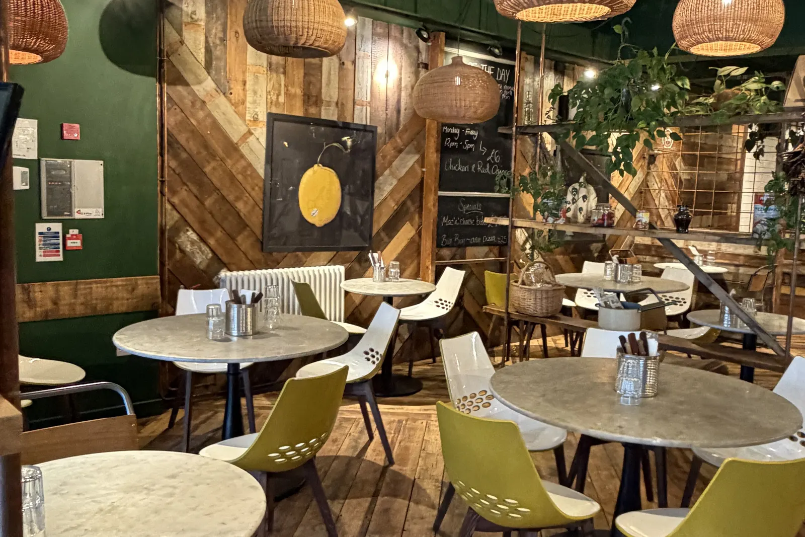 Luben's dining room on Rendezvous Street, Folkestone, with woven lamps, wood panelling and green chairs