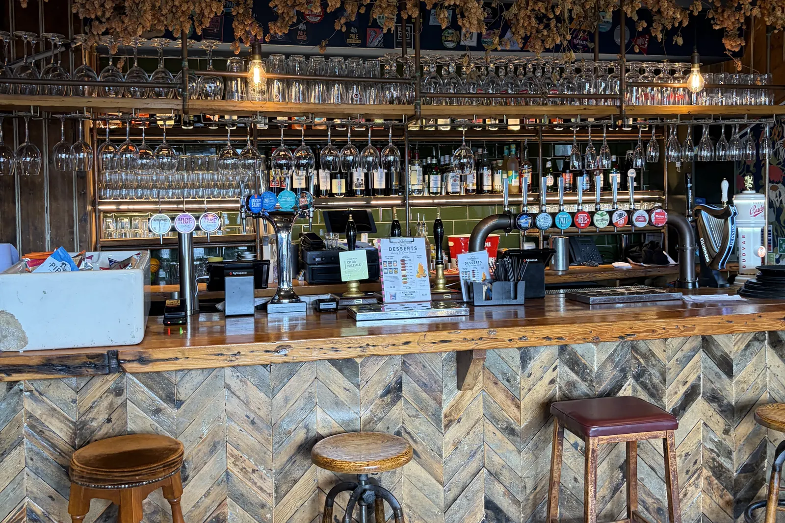 The herringbone-panelled bar with stools and rattan lamps at Harbour Inn, Folkestone harbour