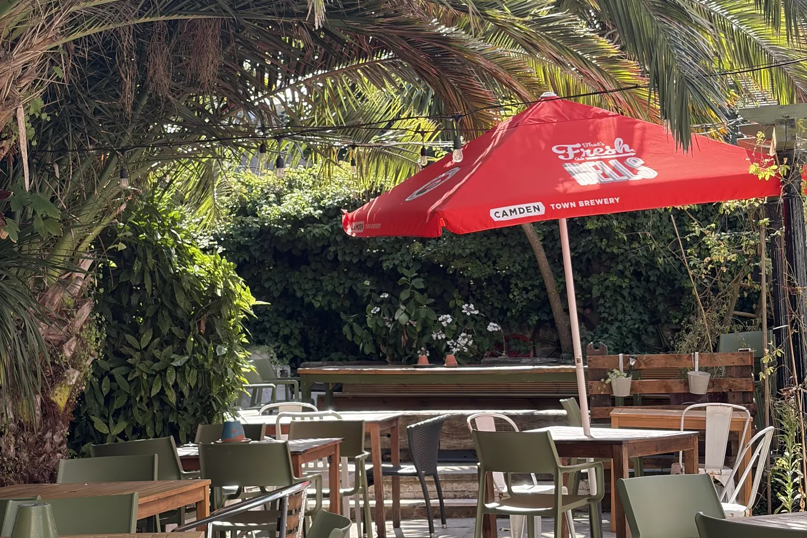 The Pullman's palm-shaded beer garden in Folkestone, with a red parasol over the tables