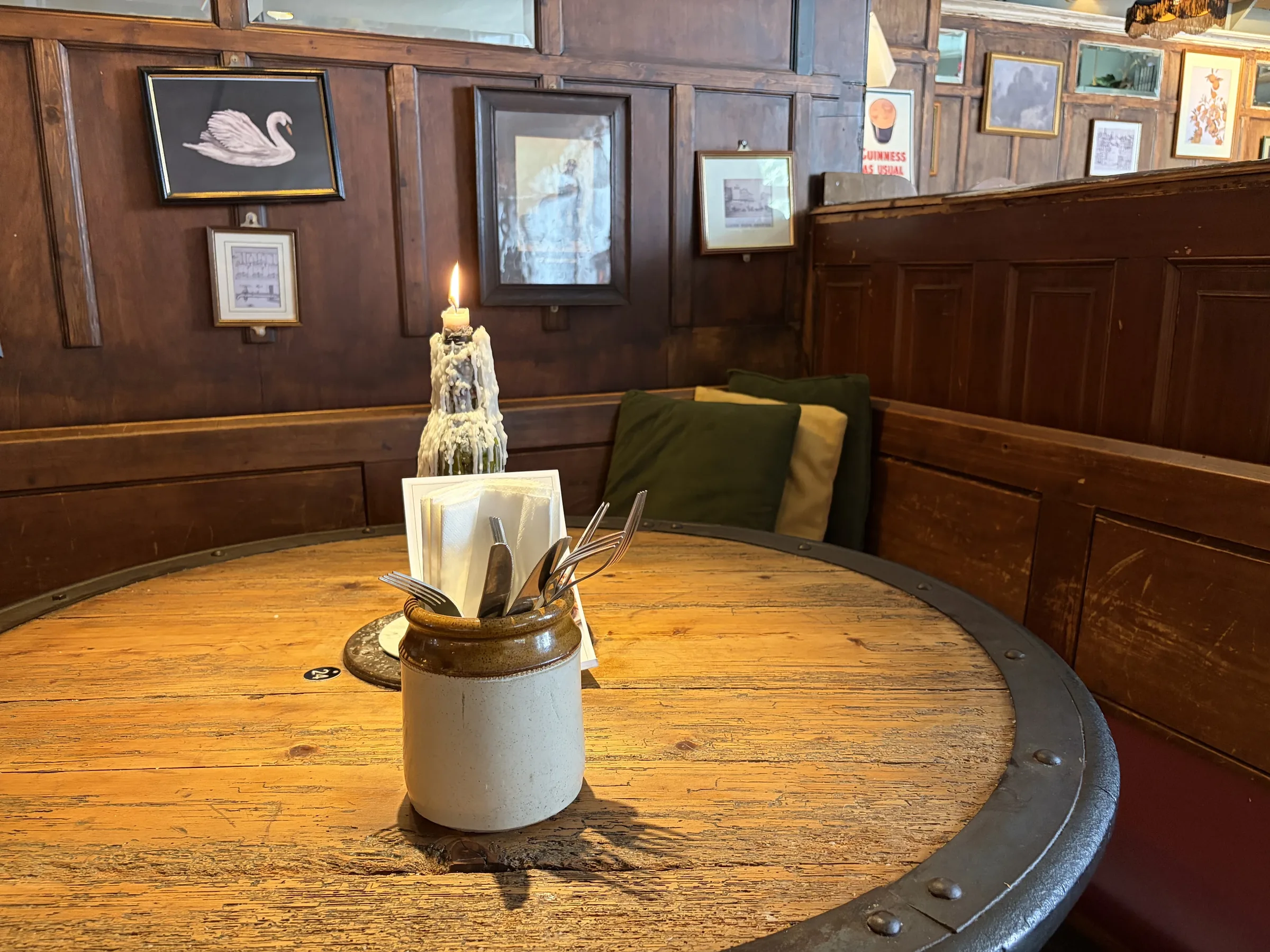 A candlelit round table in a panelled booth at The Pullman, Folkestone