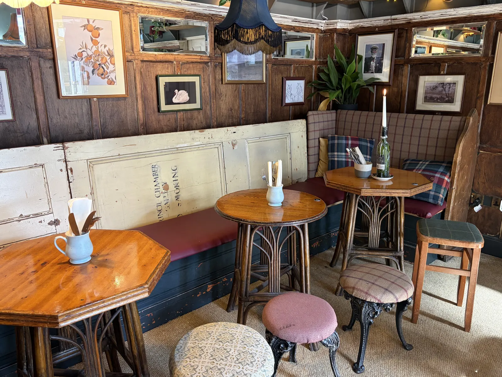The wood-panelled snug at The Pullman, Folkestone, with round tables, stools and framed pictures