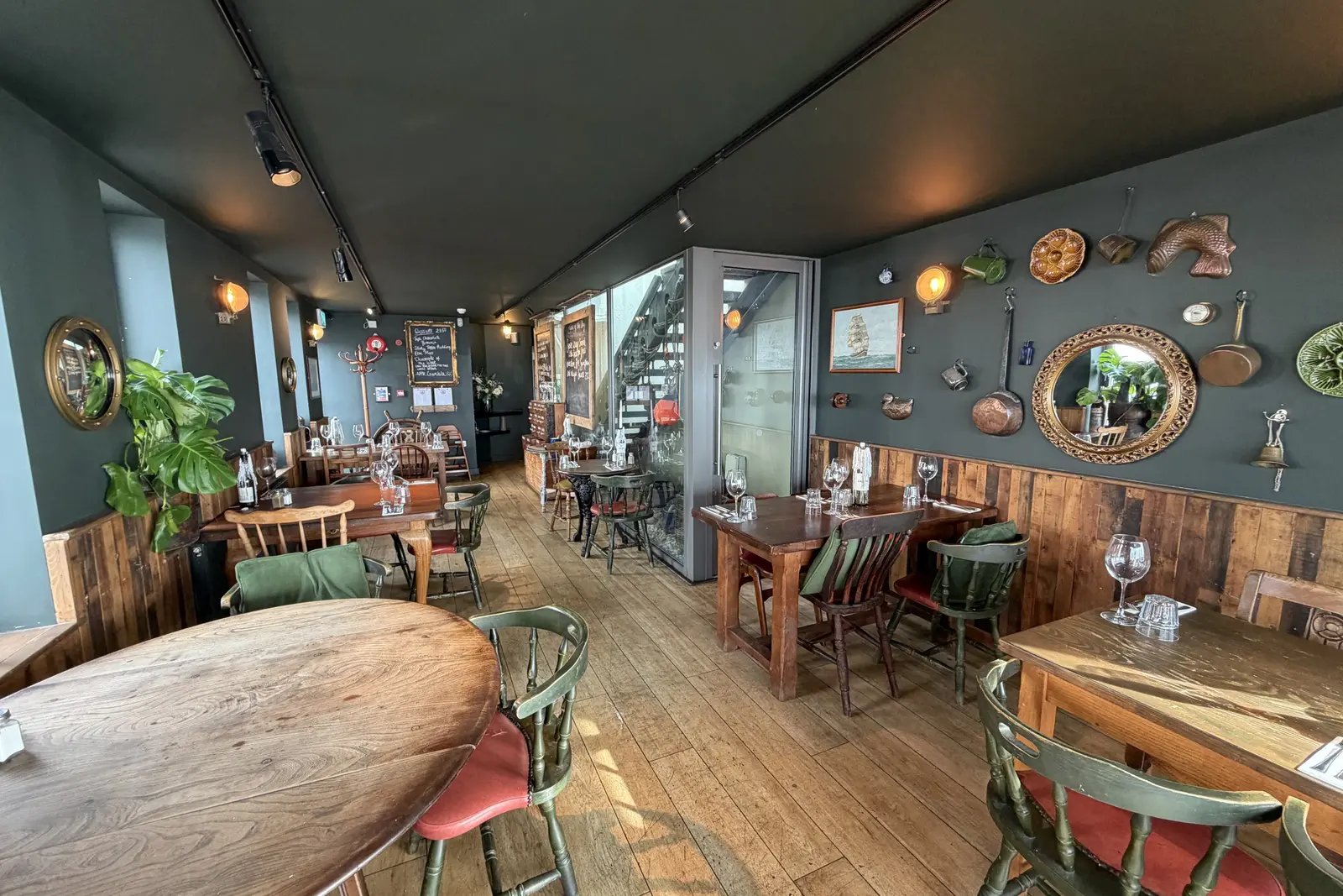 The long dining room at The Ship Inn, Sandgate, with dark green walls, mirrors and wooden tables